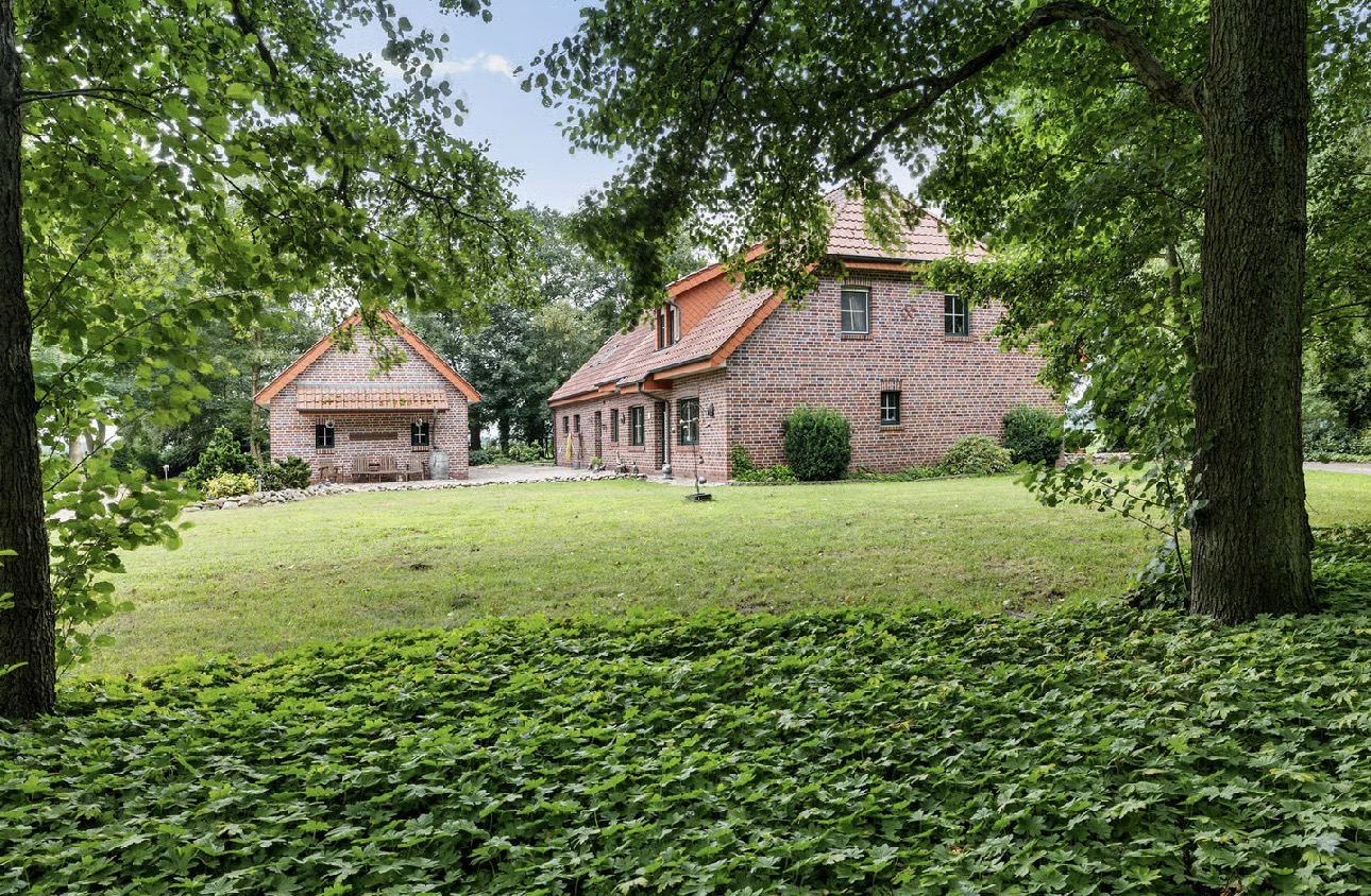 De b&b van Woestenij: rode baksteen, tussen de bomen aan een groot gazon