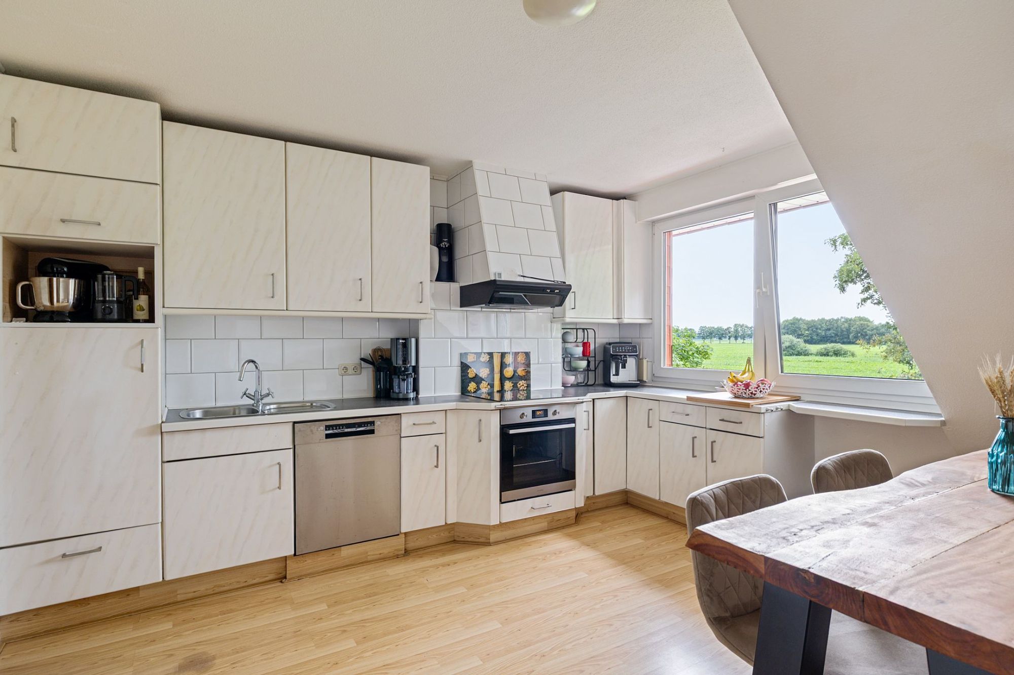 Lichte keuken met eettafel en een raam met uitzicht over de weilanden