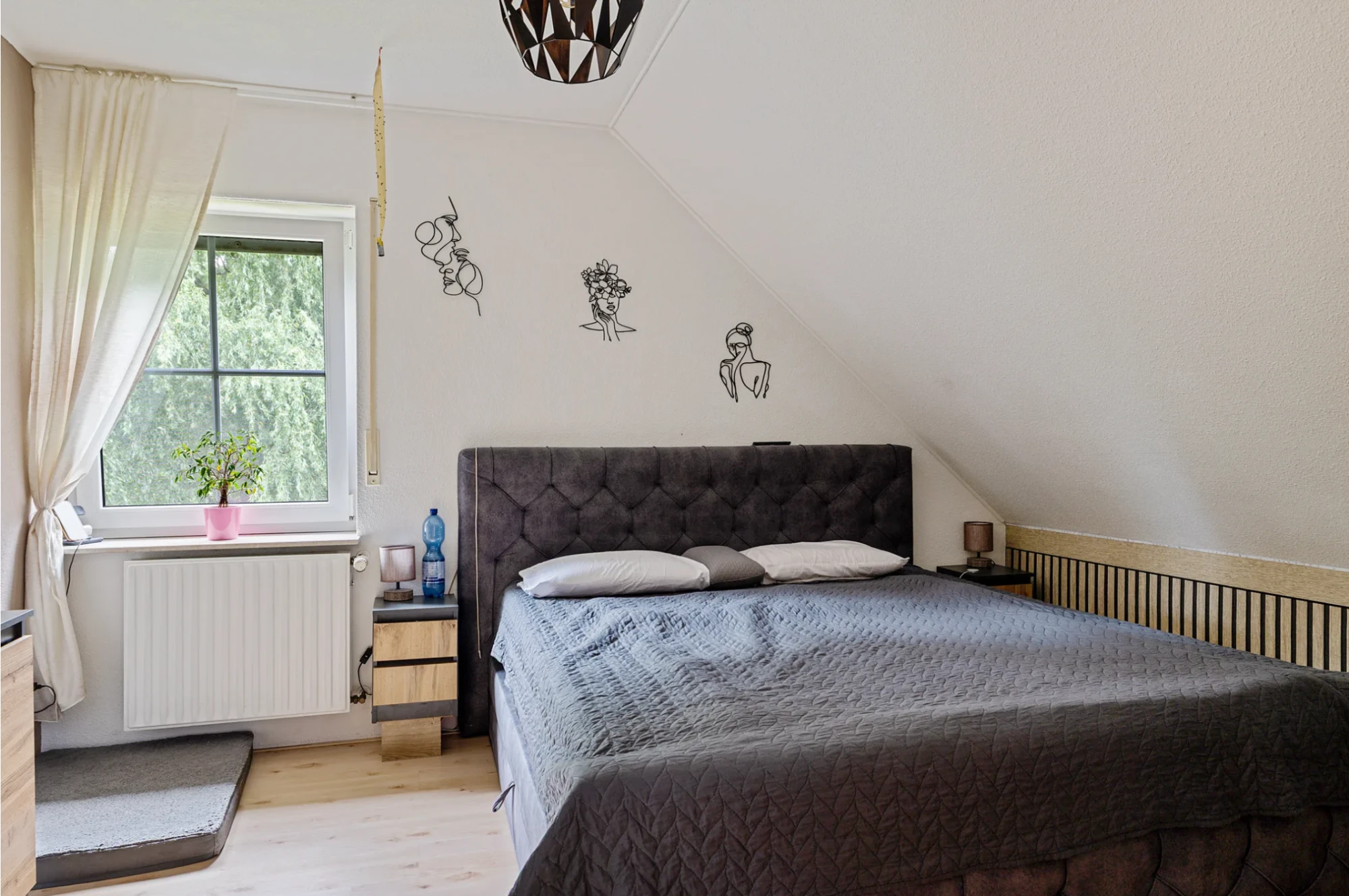 Slaapkamer onder het schuine dak met een tweepersoonsbed