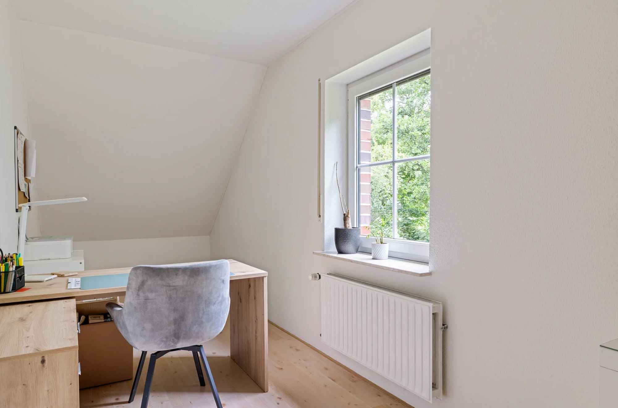 Lichte kamer met bureau en een raam met uitzicht op het groen